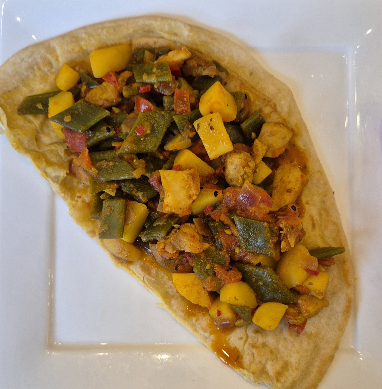 Een bord roti met kip, aardappel en snijbonen.