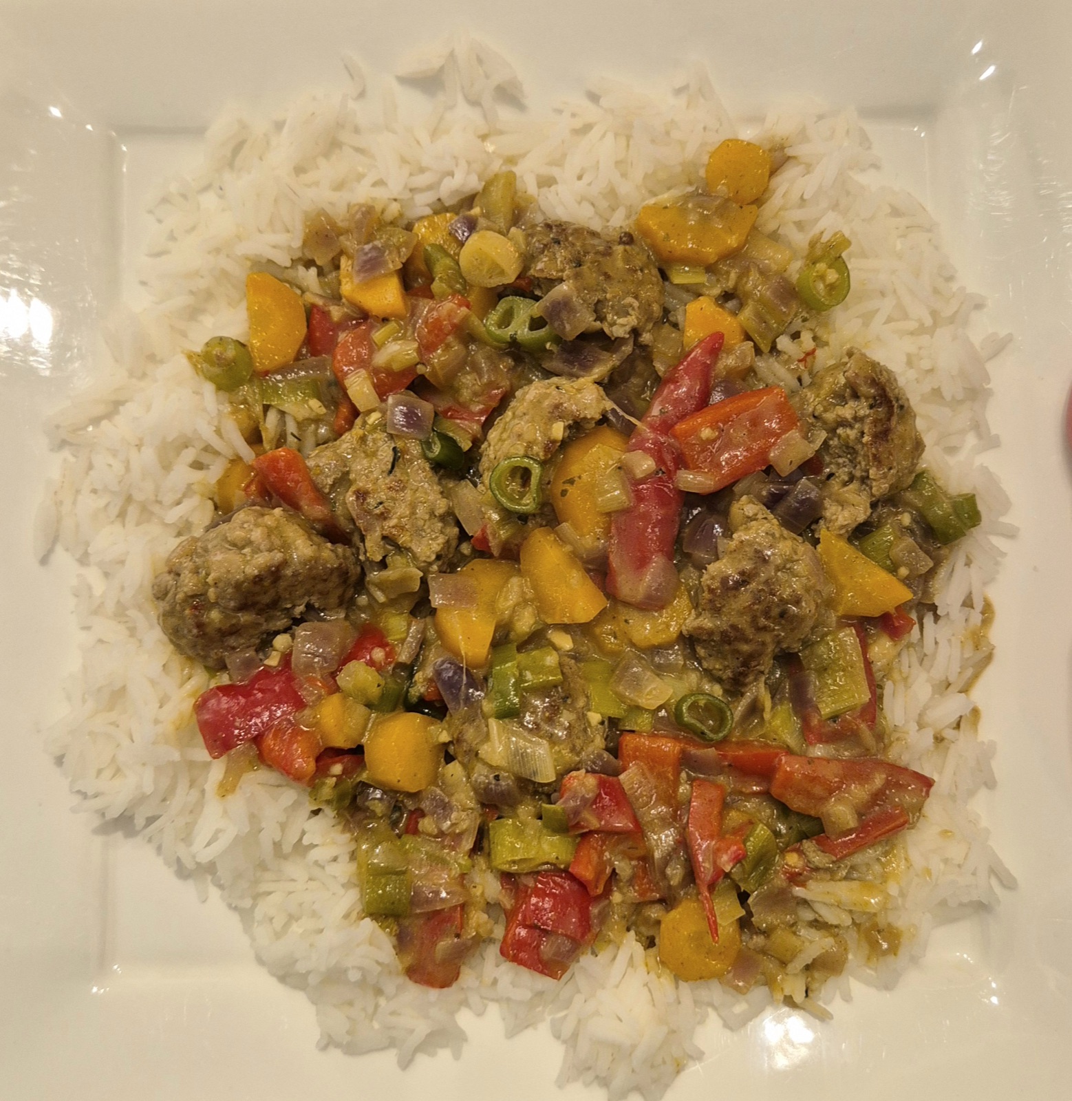 Een diep bord Thaise groene curry met gehaktballetjes, kokosmelk en wortel.